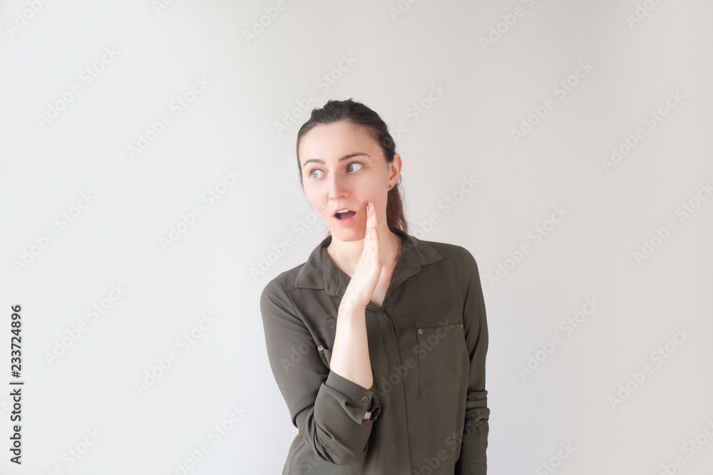 Portrait of curious pretty Caucasian girl talking aside and holding hand near mouth. Young woman looking left and sharing secrets. Gossip concept Portrait of curious pretty Caucasian girl talking aside and holding hand near mouth. Young woman looking left and sharing secrets. Gossip concept