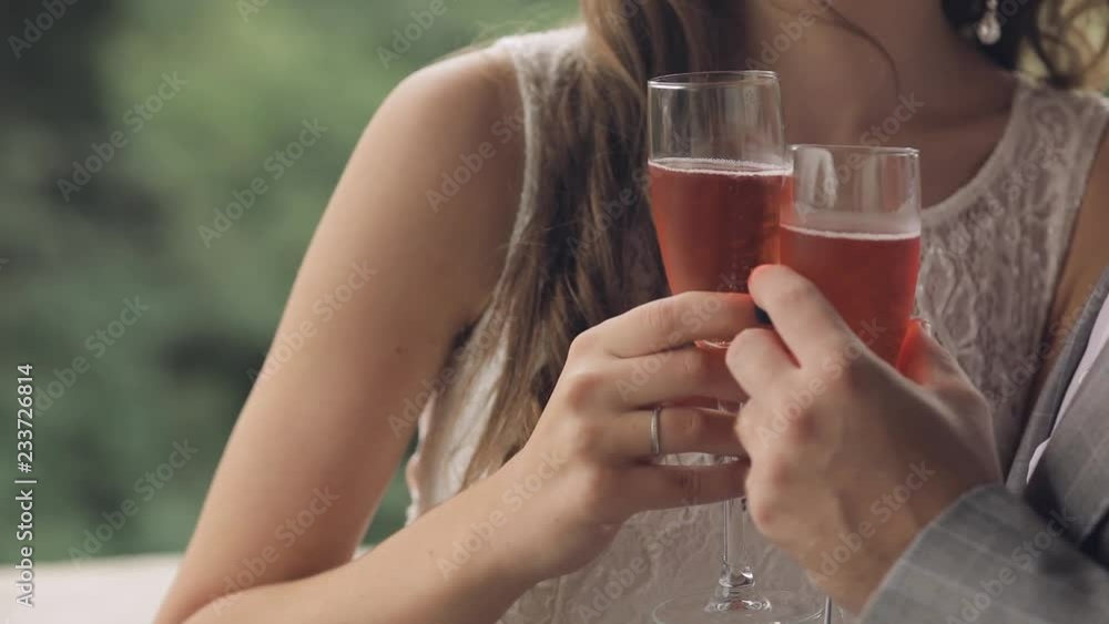 Two champagne glasses holds a young wedding couple. Lovely groom and bride. Wedding day. Slow motion Two champagne glasses holds a young wedding couple. Lovely groom and bride. Wedding day. Slow motion
