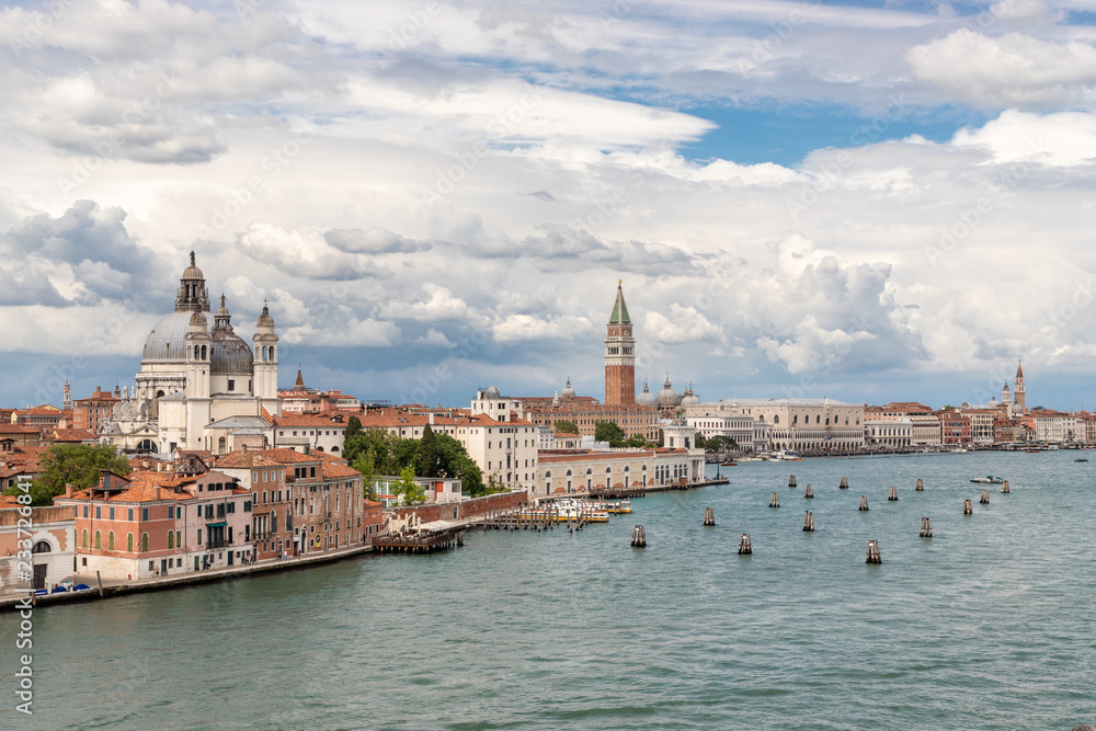 View of Venice from the sea. On the right side of the frame you can see the water. On the left side of the frame is the city. Blue sky with various clouds.