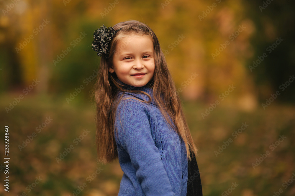 Portrait of little girl in the autumn park. Girl model poses to photographer. Happy child Portrait of little girl in the autumn park. Girl model poses to photographer. Happy child