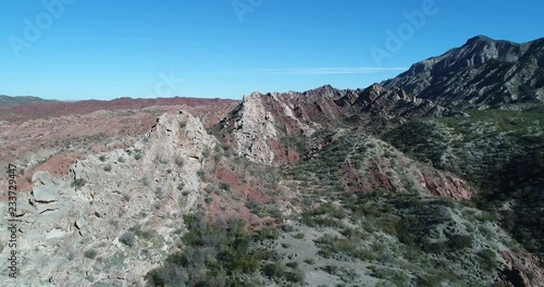 Aerial drone scene of red and white landscape of folded mountains. Camera ascends showig general view of natural colorful layers that get lost in the horizon. Huaco, San Juan province, Argentina photo