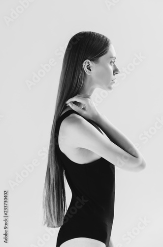 Black and white shot of Fashionable woman posing in black bodysuit, on grey