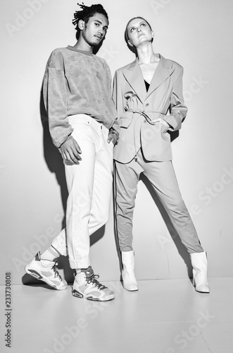 Black and white shot of Casual couple in red leaning against a grey wall