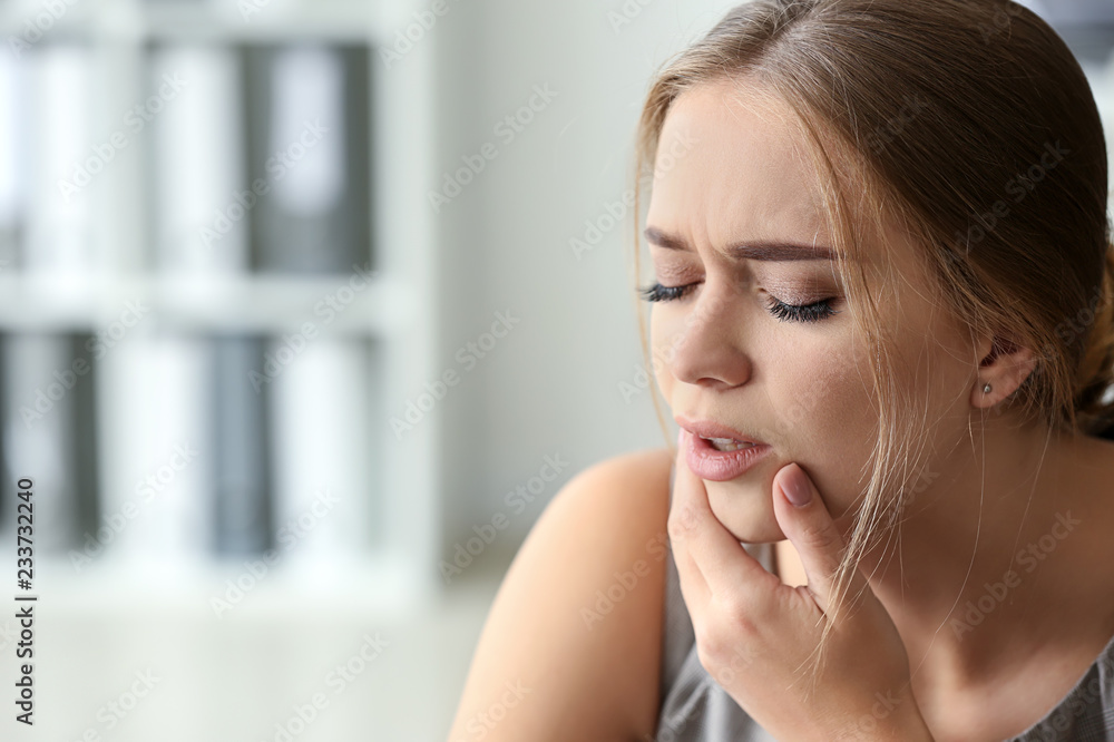 Young woman suffering from toothache in office Young woman suffering from toothache in office
