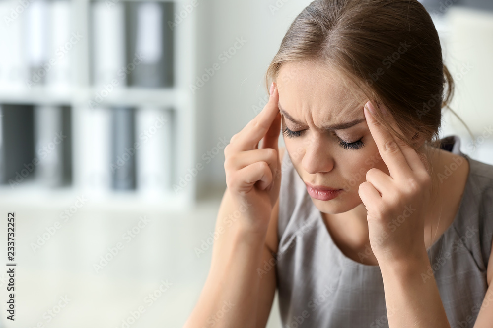 Young woman suffering from headache in office Young woman suffering from headache in office