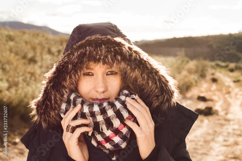 Close-up of a young woman with a coat and hood on