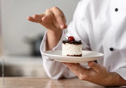 Obraz  z motywem Male chef with tasty dessert in kitchen, closeup