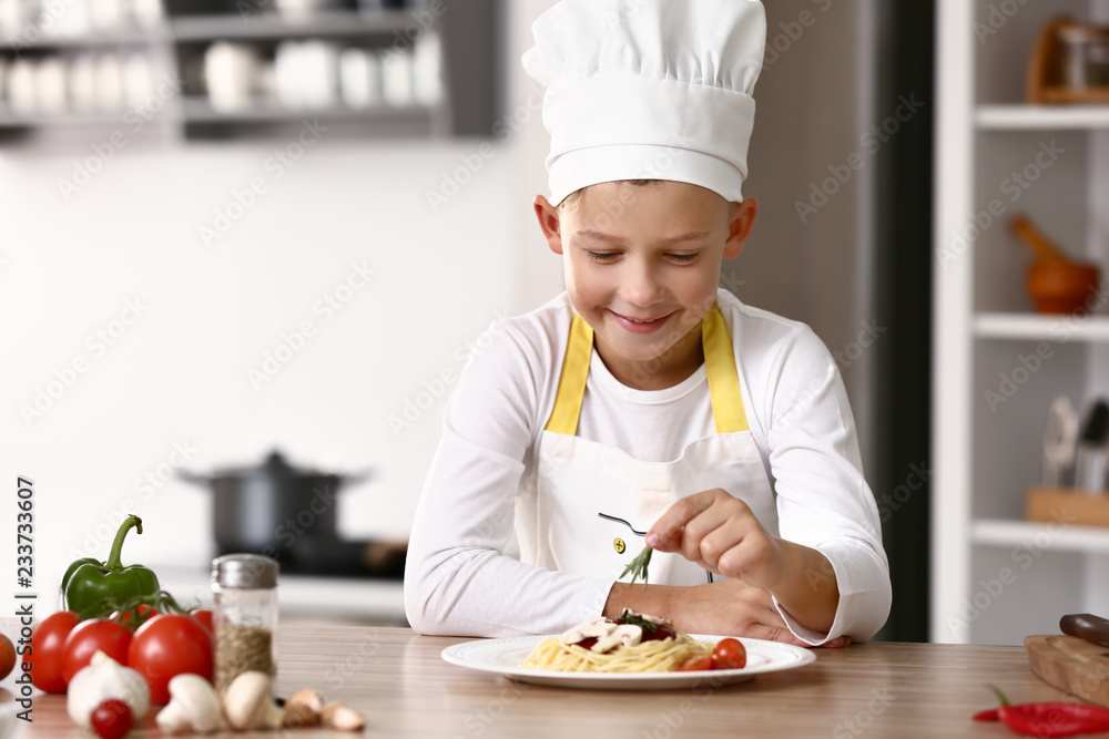 Cute little chef cooking tasty dish in kitchen Cute little chef cooking tasty dish in kitchen