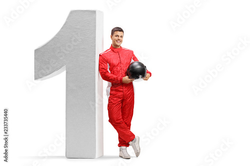Racer leaning against big sized number one and holding a helmet