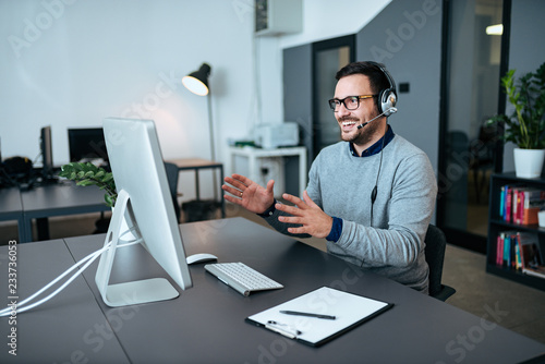 Foto Happy handsome operator with headset working in the modern office