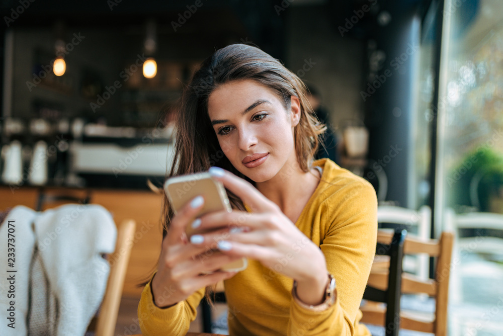 Beautiful girl looking at smartphone in the cafe.