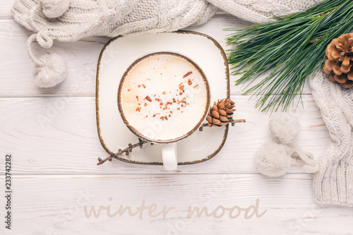Winter mood. Cappuccino  a branch of a pine tree and knitted accessories. Toned photo