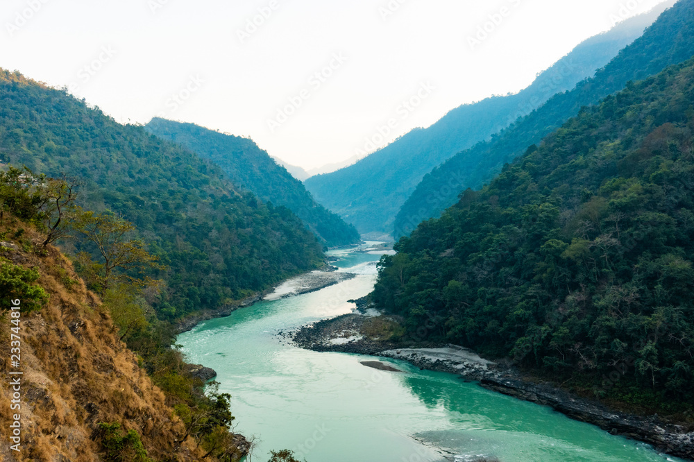 Spectacular view of the sacred Ganges river flowing through the green mountains of Rishikesh, Uttarakhand, India.