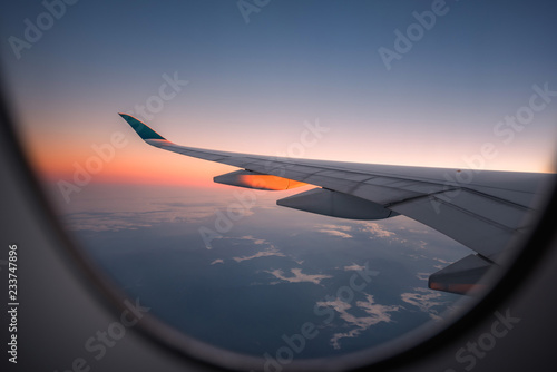 Silhouette wing of an airplane at sunrise view through the window.
