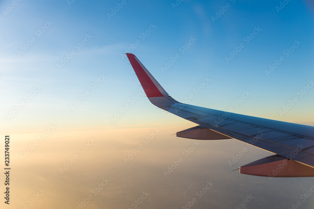 wing of airplane on cloud at sunset. subject is blurred.