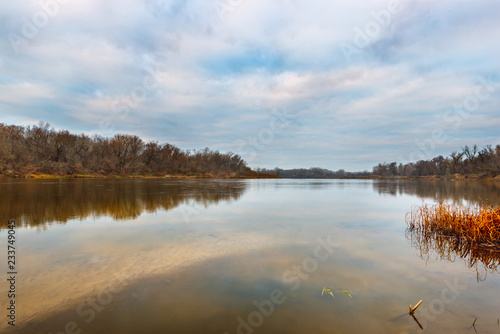 The autumn landscape with the calm river, the bare forest without leaves and overcast sky. Stogovskaya Spit, Don river, Rostov-on-Don region, Russia