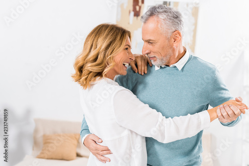 selective focus of mature couple looking at each other while dancing at home