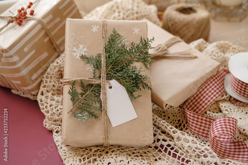 Blank Gift tag on Classy vintage Christmas gift box on lace tablecloth background. Christmas presents with handmade decoration. Close up. Mockup. Copy space.