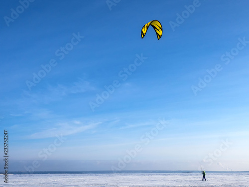 Kite surfing on the winter sea. The concept of freedom. Young men, skiing ski under sail on a frozen lake in the mountains.