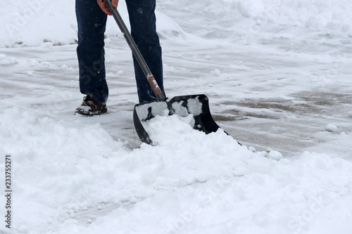 Winter snowy day background. Man shoveling snow on driveway during a heavy snowfall. Close up composition. © Maryna