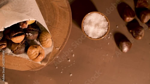 Roasted chestnuts in a paper cone, on a rustic kitchen countertop.