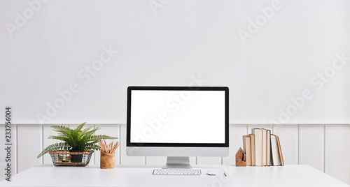 Desktop screen close up, book, vase of plant and classic wall background.