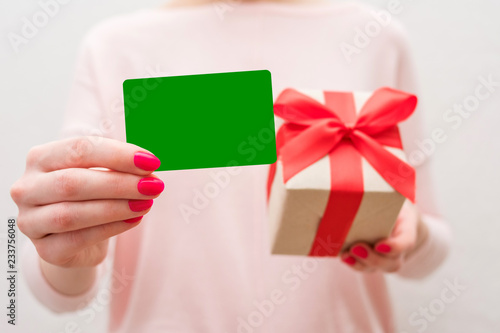 Woman holding a box with a gift, showing business card to the camera, front view, close up, background with copy space, for advertising or slogan