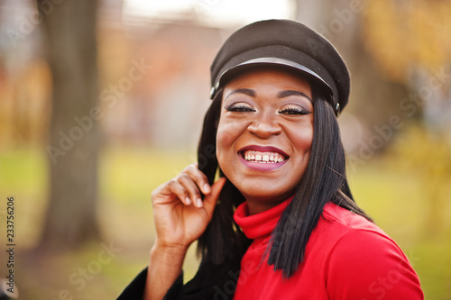 Close up portrait of african american fashion girl in coat and newsboy cap posed at street.