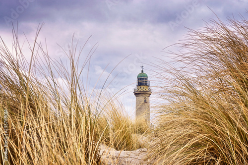 Fototapeta Naklejka Na Ścianę i Meble -  Very close to the dune grass with lighthouse in the background. Warnemünde, Germany