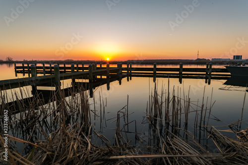Bright and colorful sunset over a lake with a pier along the lake 'Rottemeren' in The Netherlands © Menyhert