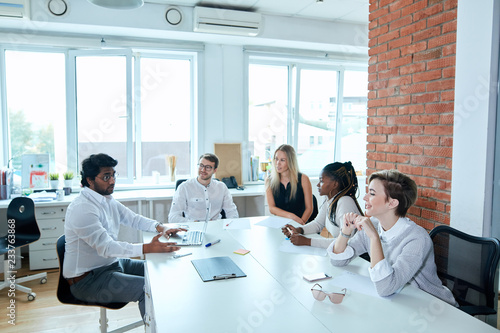 Successful mixed race young business people are talking during the coffee break in office with loft design. interests, people, career concept photo