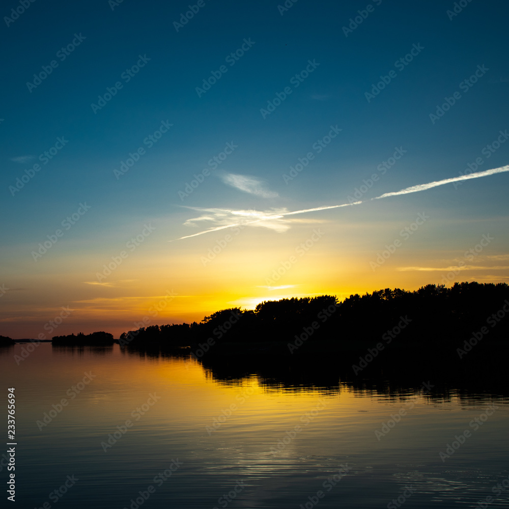 A beautiful deep blue sky at sunset accented by a white spangled cloud, a few days after midsummer, viewed from a cove on the Island of Nicklösa in the Åland Islands, Finland. A beautiful deep blue sky at sunset accented by a white spangled cloud, a few days after midsummer, viewed from a cove on the Island of Nicklösa in the Åland Islands, Finland.