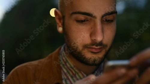 Portrait of young man using smart phone, face illuminated by screen light – night life, intenret, communication concept photo