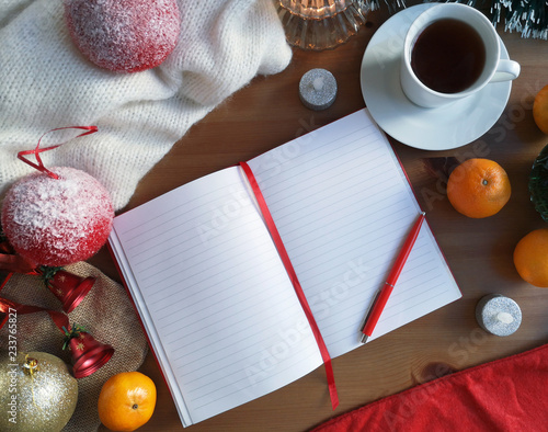 An open empty notebook on the wooden background with christmas and new year decoration, candles, oranges, christmas balls and cup of coffee