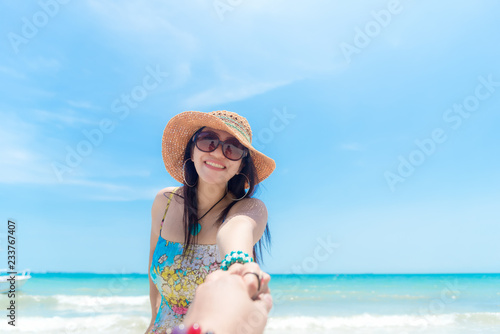 Romantic scene of young love couple vacations in the beach. Hand man holding hand woman in dress and hat walking into a sea, in love and enjoy relax in honeymoon day  Travel and Summer Concept © freebird7977