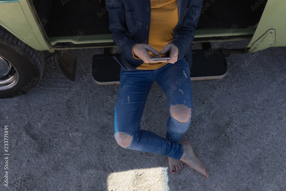 Woman using mobile phone sitting on open van door Woman using mobile phone sitting on open van door