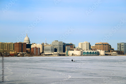 Downtown skyline of Madison, the capital city of Wisconsin, USA. Winter day view with State Capitol building and Monona Terrace across the frozen lake Monona from the Olin Park. Fisher on the ice. photo