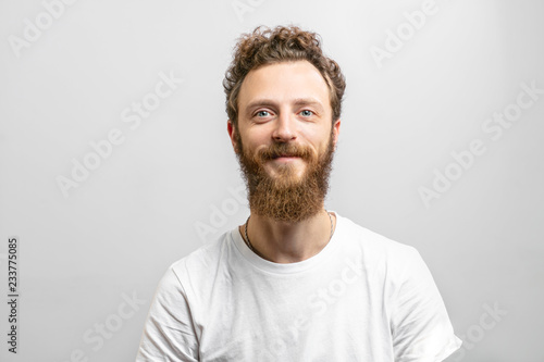 Bild auf Leinwand Portrait of young handsome softie, good-looking kind hipster man with beard smiling and looking at camera over white background