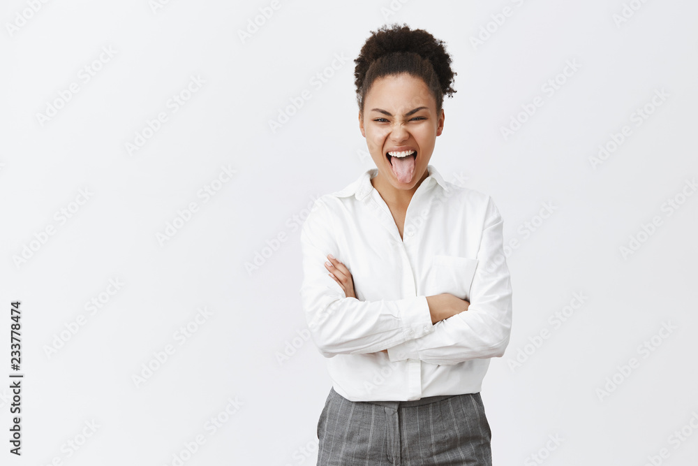TGIF, no work today. Charming playful and emotive african-american woman in white shirt and pants, holding hands crossed in confident pose and sticking out tongue, spending evening in bar, having fun TGIF, no work today. Charming playful and emotive african-american woman in white shirt and pants, holding hands crossed in confident pose and sticking out tongue, spending evening in bar, having fun