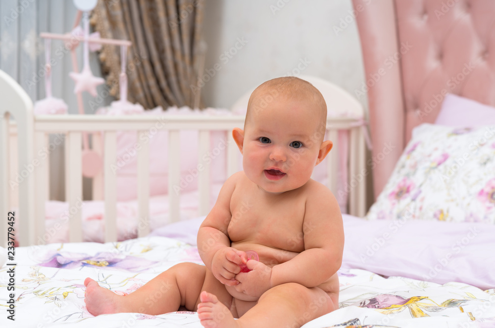 Happy friendly little baby girl on a bed