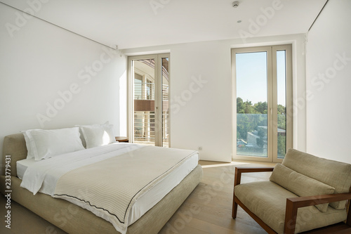Interior of a spacious light bedroom with windows in a luxury villa