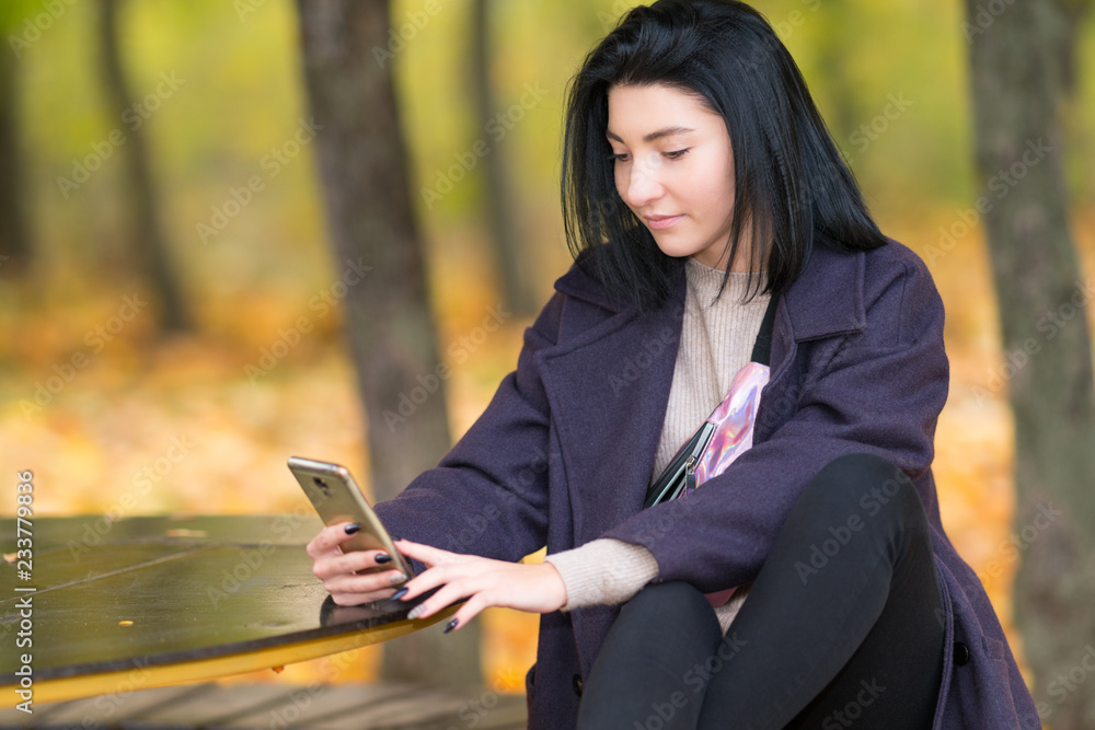 Fototapeta premium Attractive young woman texting on her mobile phone