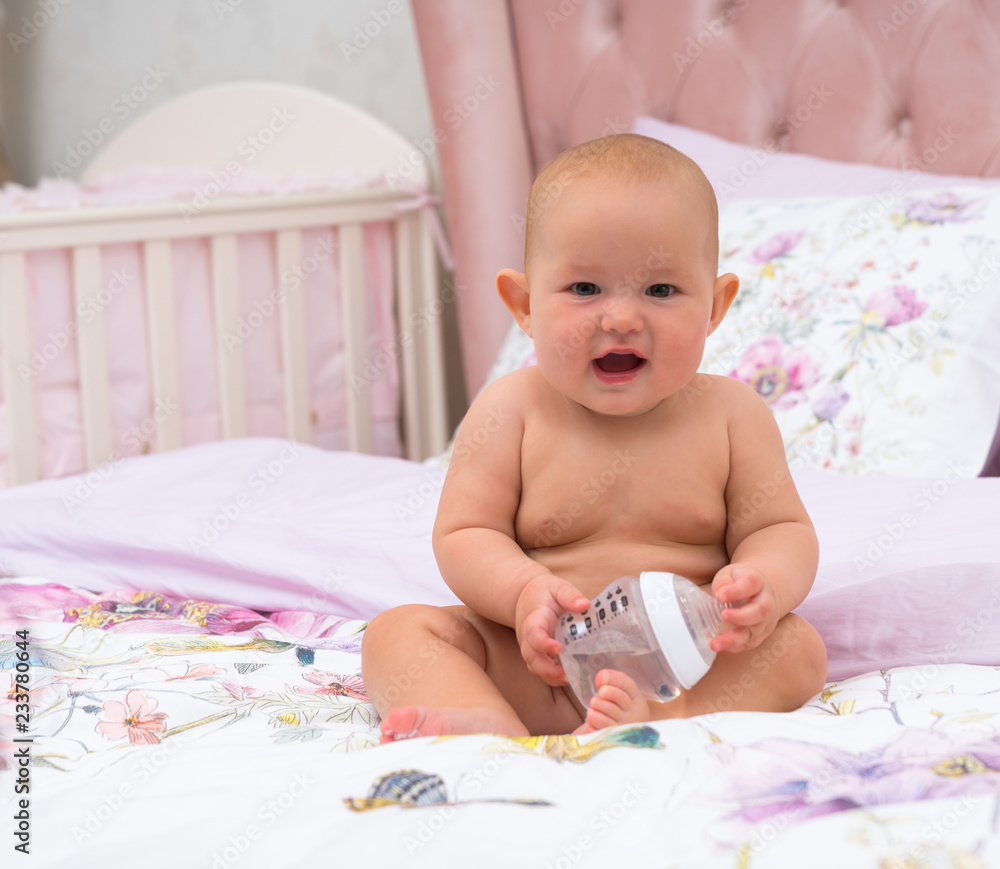Cute little baby sitting with plastic water bottle
