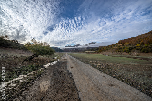 Old road in ruins that is generally flooded by the waters of the reservoir of Riaño in Leon, Spain. In the background you see the mountains between the morning mists.  photo