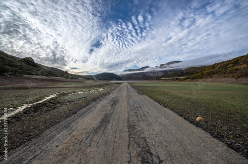 Old road in ruins that is generally flooded by the waters of the reservoir of Riaño in Leon, Spain. In the background you see the mountains between the morning mists. 