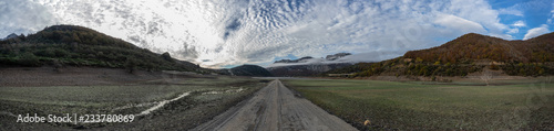 Panoramic photo of a valley with a old ruined road that is generally flooded by the waters of the reservoir of Riaño in Leon, Spain. In the background you see the mountains between the morning mists.  photo
