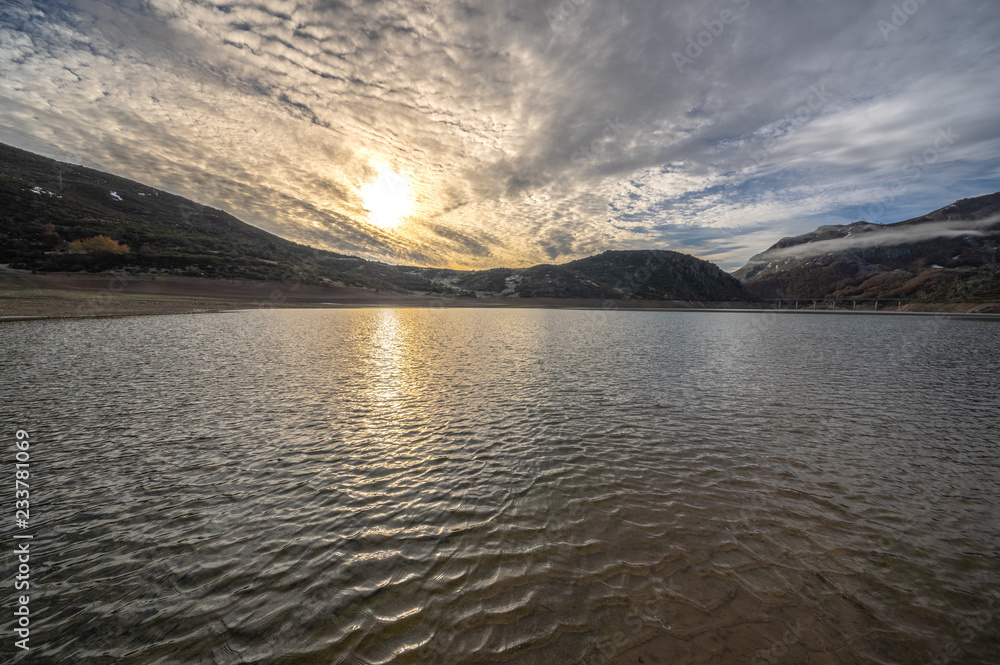 Reservoir of Riaño in Leon, Spain. You see the sun among the clouds.