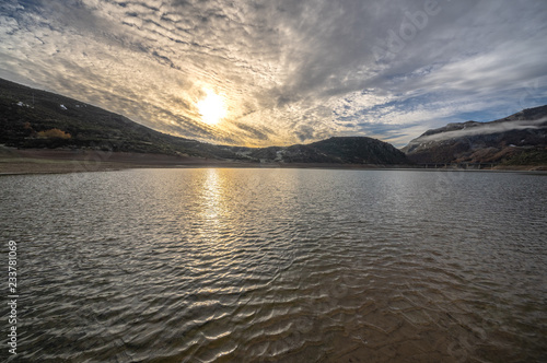 Reservoir of Riaño in Leon, Spain. You see the sun among the clouds. photo