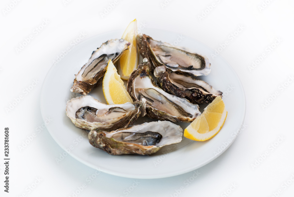 Fresh oyster. Raw fresh oyster on white round plate, image isolated, with soft focus. Restaurant delicacy. Saltwater oyster, soft focus Fresh oyster. Raw fresh oyster on white round plate, image isolated, with soft focus. Restaurant delicacy. Saltwater oyster, soft focus