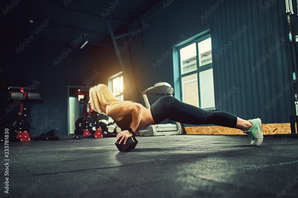 Young athletic girl doing stretching exercises in the modern gym.